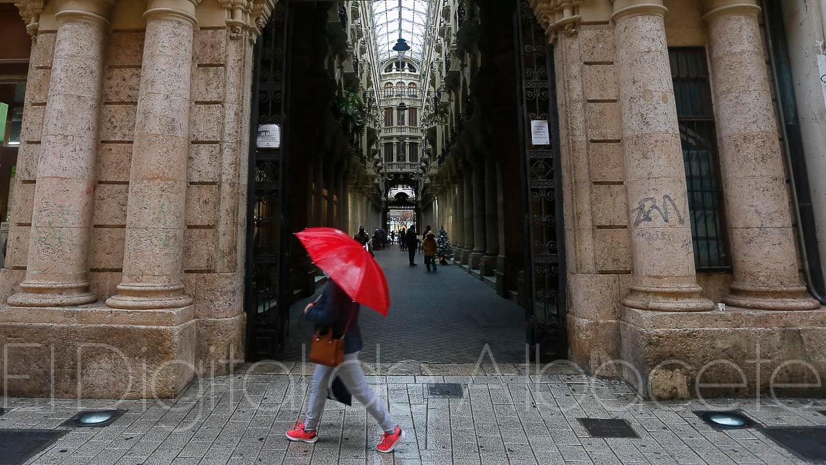 Una mujer camina bajo la lluvia frente al Pasaje Lodares de Albacete